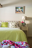 Floral scarf with lime green blanket on double bed walls in Strong White Wiltshire cottage UK