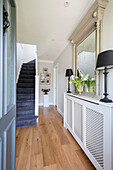 Pair of lamps and mirror on radiator shelf in hallway of Surrey cottage UK