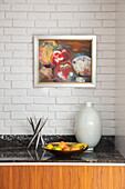 Modern art above worktop with vase and fruitbowl in London home UK