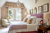 Floral curtains in sunlit bedroom with framed butterfly prints Wales UK