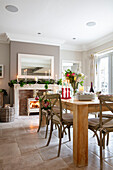 Mirror above lit fire with wooden dining table and limestone floor Hampshire UK