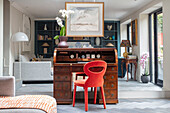 Bright red chair at 1930s rolltop desk with mirrored wall in Victorian cottage London UK