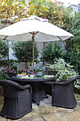 Parasol and black wicker chairs on terrace of Victorian townhouse London UK