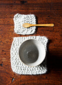 Ceramic bowl and wooden spoon on knitted placemats on wooden tabletop in Isle of Wight home UK