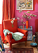 Roter Sessel mit Decke und Frühlingsblumen im Wohnzimmer auf der Isle of Wight, UK