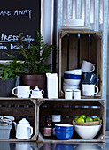 Café-Inneneinrichtung mit upgecycelten Holzkisten als Regale für Emaille-Tassen, Schalen und Teekannen mit Topfpflanzen