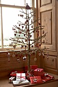 Rot-weißer Weihnachtsschmuck an einem Baum, umgeben von Geschenken auf einer Fensterbank