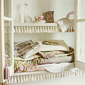 White painted glass fronted storage cabinet containing fabrics and homeware