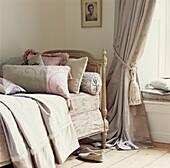 Country style bedroom with ornate single bed with scatter cushions and a window seat