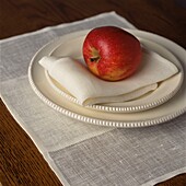 Neutraler Teller und gedeckter Tisch mit einem Apfel