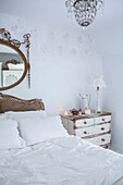 Scandinavian style bedroom with distressed paintwork and vintage bed and chest of drawers