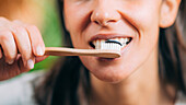 Woman brushing teeth with black charcoal toothpaste