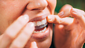 Woman using teeth whitening strips