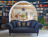 Blue sofa in front of bookshelf, view of dining area with bouquet of flowers