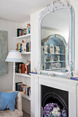 Fireplace with floral arrangement, large mirror and porcelain collection in the living room