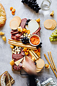 Cheese board with crackers, salami, grissini, grapes and dried apricots