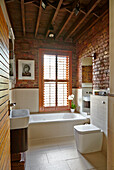 Renovated bathroom with brick walls and wooden beamed ceiling