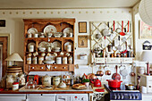Holzregal mit Vorratsdosen und Geschirr, daneben verschiedene Küchenutensilien an Vintage Regal in der Küche