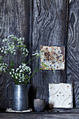 Metal pot with wildflowers in front of a rustic wooden wall