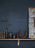 Decorative still life with vintage objects on a wooden shelf in front of a dark wall