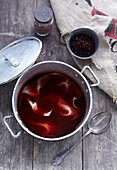 Preparation of natural dye with red leaves in a pot on a wooden surface