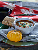 Herbstliche Tischdekoration mit Kürbissuppe und Mini-Kürbis