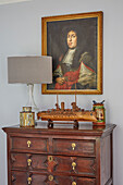 Antique chest of drawers with works of art, above a portrait painting