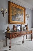 Antique console with works of art, and an oil painting hung above it