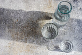 Mineralwasser in Karaffe und Gläsern auf grauem Betontisch