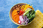 Veggie bowl with chickpeas, peppers, salad leaves, onions and sweet potato