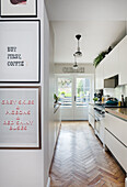 Modern kitchen with white cupboards and herringbone parquet flooring