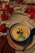 Pumpkin soup with coriander and croutons on an autumnally decorated table