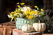 Herbstarrangement in Kuchenform mit Kürbissen und gelben Blumen