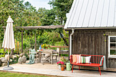 Terrace with wooden deck, garden furniture and colourful cushions in front of a wooden house
