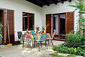 Terrace with colourful table setting and colourful chairs