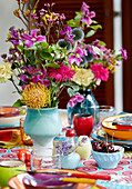 Colourful bouquet of flowers in a ceramic vase on a table with colourful tableware