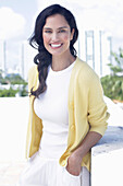 Dark-haired woman in white top and yellow cardigan