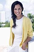 Dark-haired woman in white top and yellow cardigan