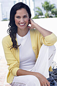 Dark-haired woman in white top, yellow cardigan and white trousers