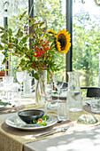 Set table with bouquet of sunflowers in front of window front