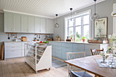 Country kitchen with sales counter as kitchen island and light grey cabinets