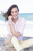 Brunette woman in pink striped blouse and light shorts on the beach