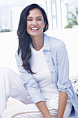 Dark-haired woman in a white top, light blue shirt and white trousers