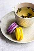 Cup of green soursop tea and macaroon pastry on concrete background