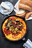 Greek omelette with sausage, aubergine and chips in a cast iron pan