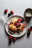 Berry cobbler with cream on a ceramic plate