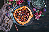 Plum galette served on a large plate and on a dark background