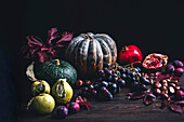 Herbstliches Stillleben mit Kürbis, Quitten, Weintrauben, Kastanien und Pflaumen
