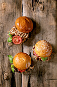 Homemade mini burgers with stew beef, tomatoes and basil on wooden background