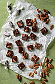 Homemade toffee salted caramel chocolate almond nuts candy on crumpled paper over green background